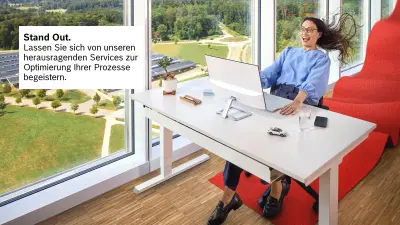 Eine Dame sitzt an einem Schreibtisch und schaut begeistert mit großen Augen auf den vor ihr stehenden Bildschirm. Sie wirkt wie nach hinten gepustet, ihre Haare fliegen und sie hält sich an dem Schreibtisch fest. 