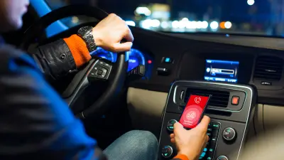 Mann sitzt im Fahrzeug und schaut auf ein Smartphone. Auf dem Bildschirm ist die App von "Sfara" zu sehen.