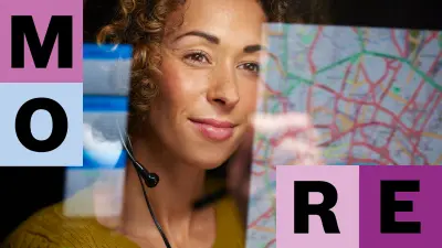 Eine Frau mit braunem, lockigen Haar sitzt vor ihrem PC-Bildschirm, durch eine Spiegelung ist eine Landkarte vor ihr auf dem Bildschirm zu sehen. 