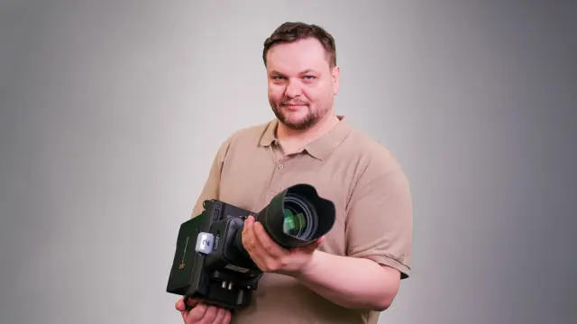 Andreas zeigt mit seinen Zeigefingern in die Kamera. 