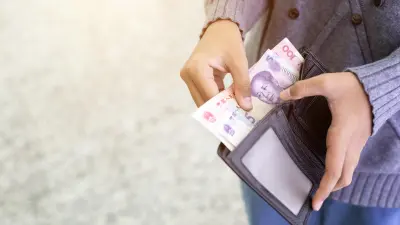 Person holds a wallet with various money bills