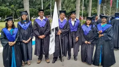 A group of Bosch employees are wearing their black robes and are standing in front of palm trees. They are smiling at the camera.