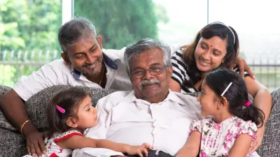Parents with two children sitting on a couch with the grandfather.