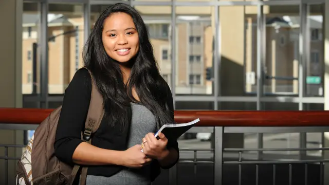 A boy with a rice bowl looks smiling at the camera