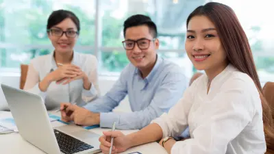 Three employees look smiling at the camera