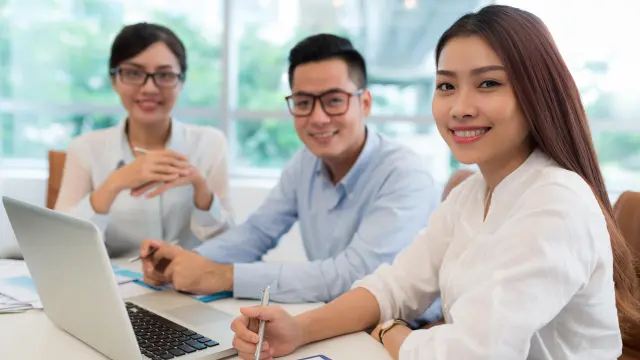 Three employees look smiling at the camera