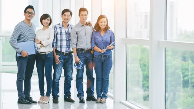 A group of employees are smiling and looking at the camera.