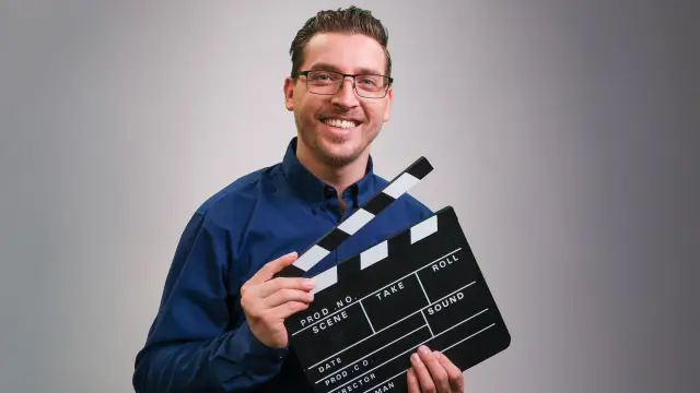 Karim lächelt in die Kamera und formt mit seinen Händen ein Herz