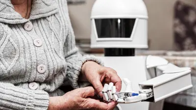 Ein Roboter gibt einer älteren Dame eine Injektionsspritze in die Hand. 