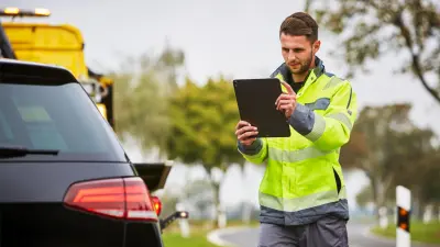 Abschleppwagenfahrer fotografiert Fahrzeug mit einem Tablet