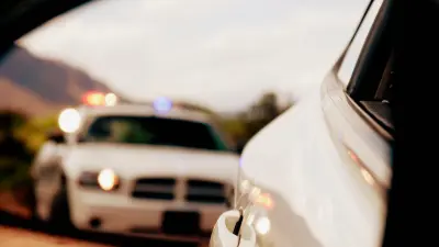 Un coche de policía con luces azules se detiene detrás de un vehículo blanco.