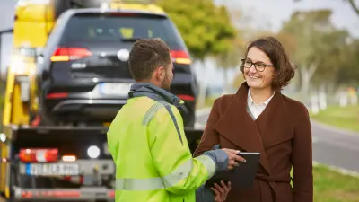 Abschleppwagenfahrer und Fahrer lächeln sich an