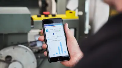 Technician holds smartphone in hand, data from the Bosch Elevator Cloud can be seen on the display