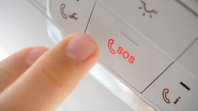 A finger presses the eCall button in a vehicle