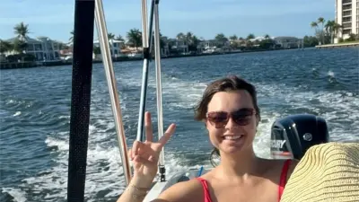 Bianca is on a boat and is smiling at the camera, showing the peace sign with her hands