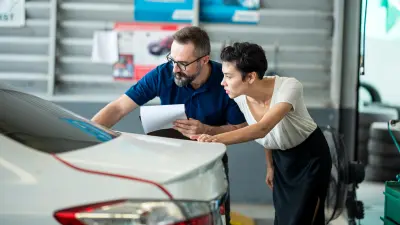 An employee in a workshop looks at a vehicle with a customer. 