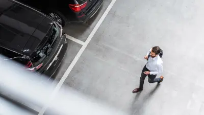 Un hombre se acerca a una fila de vehículos estacionados en un aparcamiento