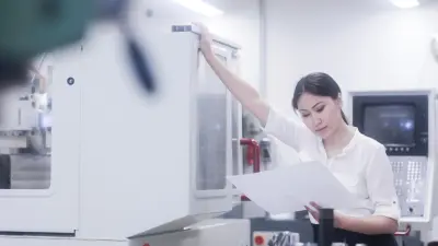 An employee in a laboratory stands in front of a medical device and looks questioningly at an instruction manual.
