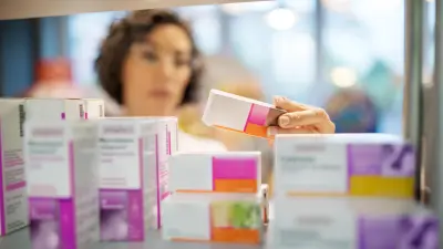 A pharmacy employee sorts medicines on a shelf.
